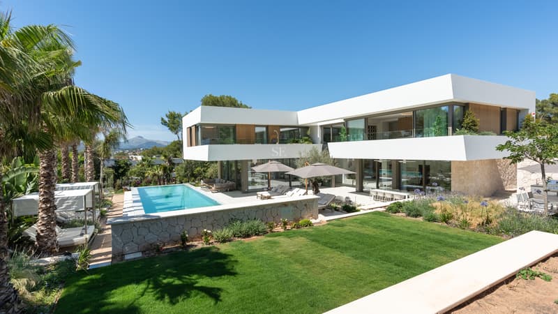 Moderne weiße zweistöckige Villa mit türkisfarbenem Pool, gepflegtem Rasen und mediterranem Garten.