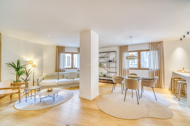 Espacioso salón de planta abierta con suelos de roble claro, mobiliario neutro y zona de comedor integrada.