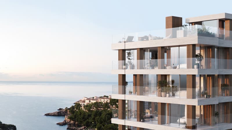 Modern multi-story building with stone facade, glass balconies, and panoramic sea views at sunset.