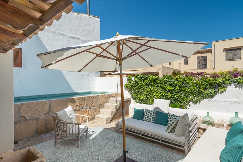 Privat Innergård med Pool och Lounge Solig medelhavsinspirerad uteplats med upphöjd stenpool, vit soffa och stort parasoll.