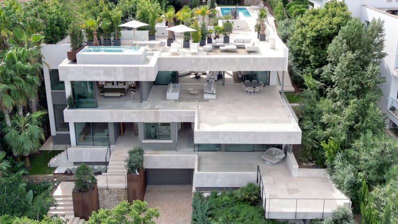 Villa de Lujo Moderna con Piscina en la Azotea Vista aérea de una villa moderna blanca de varias plantas con grandes terrazas, piscina y vegetación exuberante.