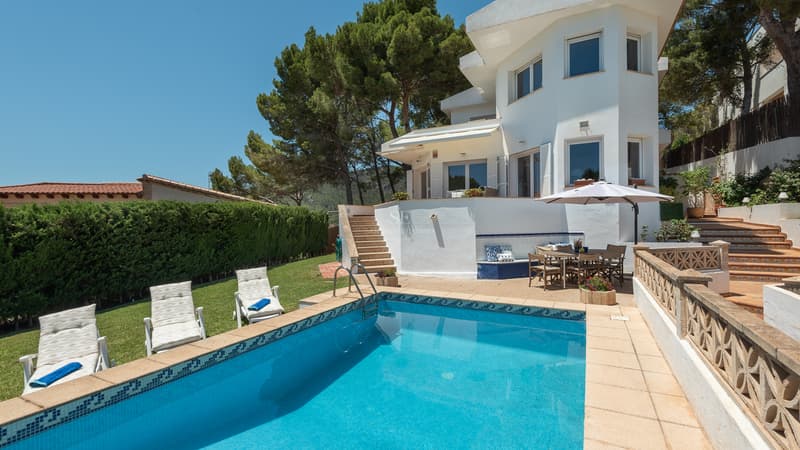 Private Pool and Mediterranean Villa Terrace White multi-story villa with a blue tiled pool, lawn with sun loungers, and an outdoor dining set under a sunshade.
