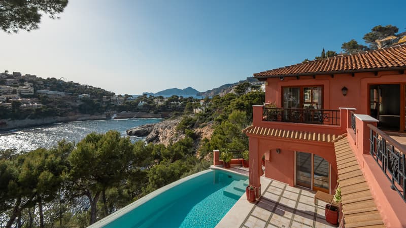 Blick von einer Terrakotta-Villa mit Infinity-Pool auf das Mittelmeer und die Küstenberge.