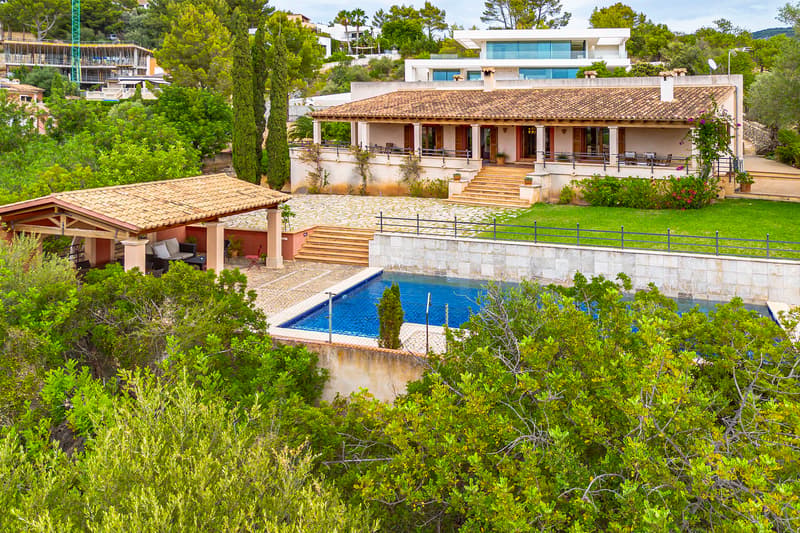 Vista exterior de una villa de estilo mediterráneo con tejado de terracota, piscina y jardines escalonados.