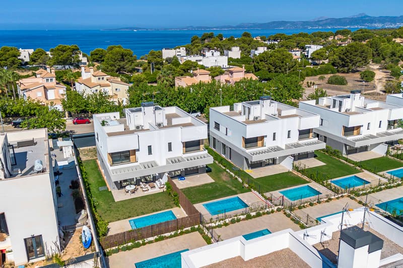 Luftaufnahme von weißen, modernen Villen mit privaten Pools und Blick auf das Mittelmeer und die Berge.