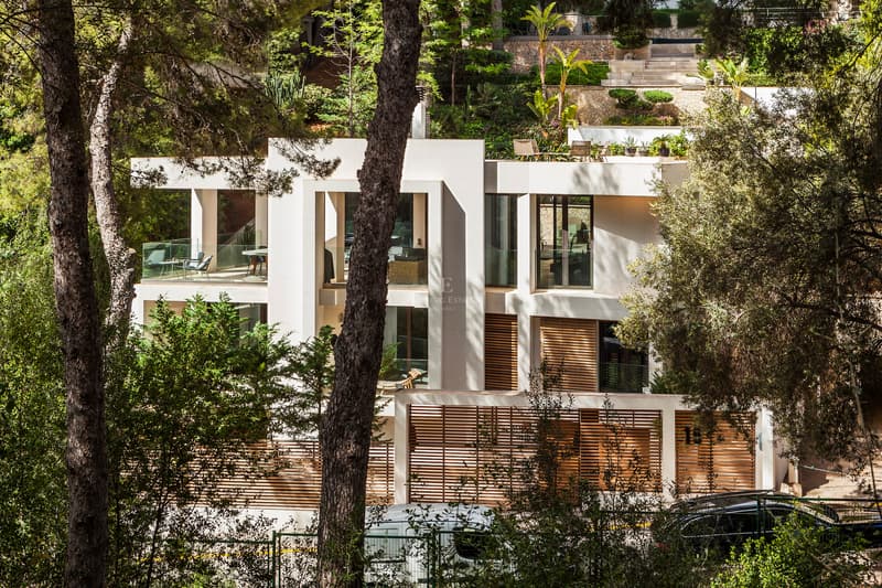 Modern Architectural Villa in Private Wooded Setting Multi-level contemporary villa with stone facade, wood slats, and glass terraces surrounded by mature pine trees.