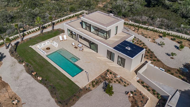 Luftaufnahme einer modernen weißen Villa mit großem Pool, Steinterrasse und minimalistischem Garten.