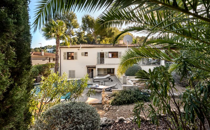 Tvåvåningsvilla med privat pool, solstolar och lummig medelhavsvegetation i solljus.