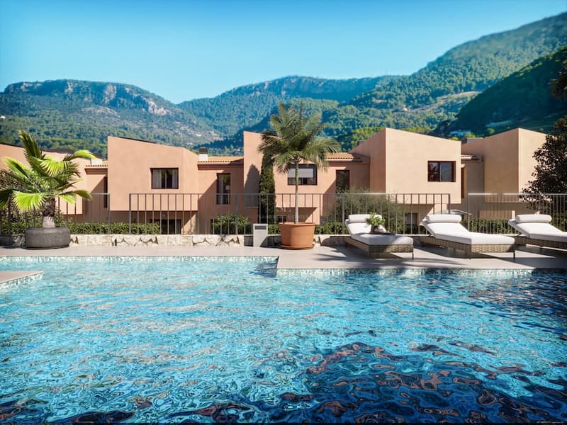 Blå pool med solstolar framför terrakottafärgade byggnader och gröna berg.