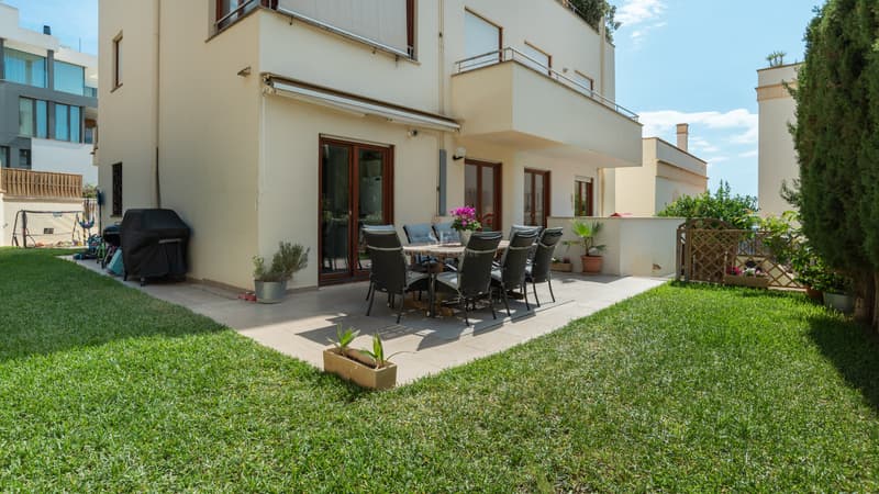 Terrasse de Jardin Privée pour Dîners en Plein Air Patio extérieur avec table à manger et chaises sur une terrasse carrelée entourée d'une pelouse verte soignée.