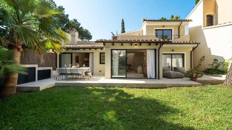 Villa Méditerranéenne avec Jardin Privé et Terrasse Façade arrière d'une villa crème avec pelouse, salle à manger extérieure et baies vitrées coulissantes.