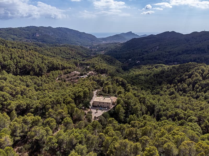 Vue Aérienne d'un Domaine Méditerranéen Isolé Vue aérienne d'une villa privée entourée d'une forêt verdoyante dans une vallée avec vue sur la mer au loin.