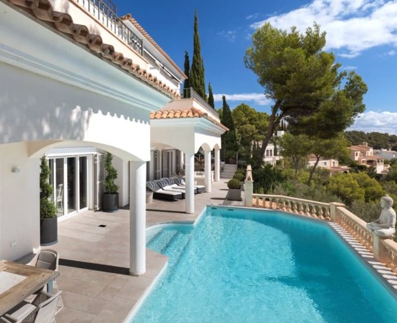 Villa méditerranéenne avec piscine privée et terrasses Vue en hauteur d'une villa blanche avec des arches, une terrasse en pierre, une piscine turquoise et des pins.