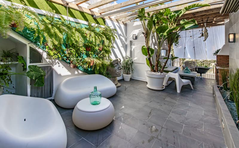 Terrasse Moderne de Luxe avec Jardin Vertical Terrasse extérieure avec canapés blancs arrondis, plantes luxuriantes, sol en pierre grise et pergola en bois.