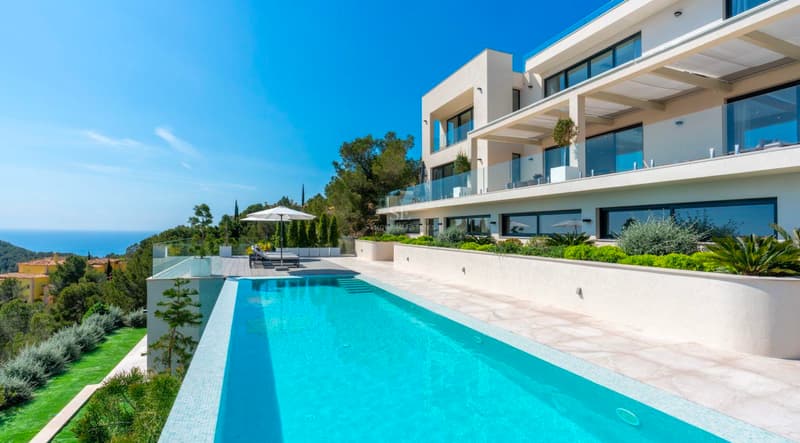 Villa moderne avec piscine à débordement et vue mer Villa moderne blanche avec piscine à débordement et vue sur mer sous un ciel bleu.