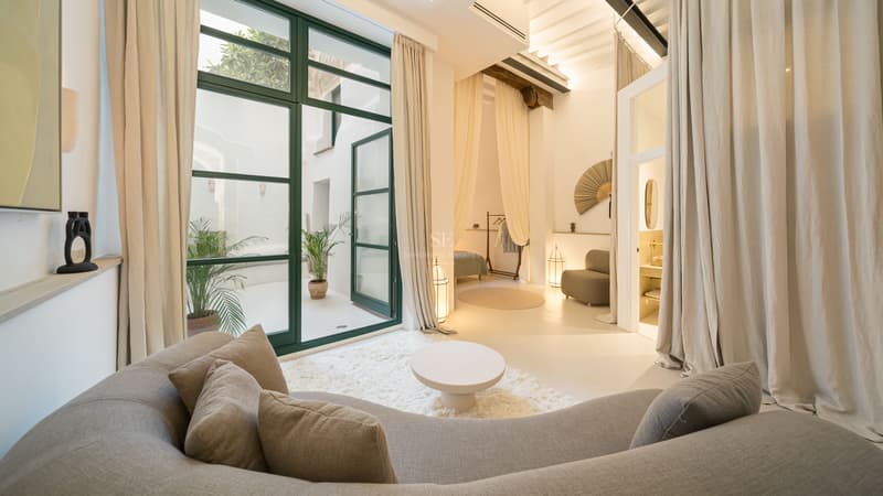 Salon contemporain élégant avec patio privé Salon moderne avec un grand canapé incurvé, un tapis à poils longs et des baies vitrées ouvrant sur un patio blanc.