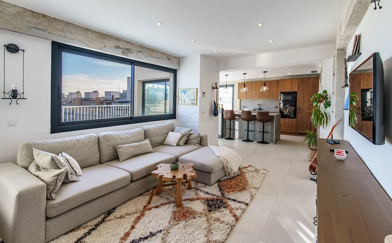 Salon moderne à aire ouverte avec vue sur la ville Salon moderne et lumineux avec un grand canapé d'angle gris, un tapis texturé et une cuisine ouverte avec vue sur la ville.