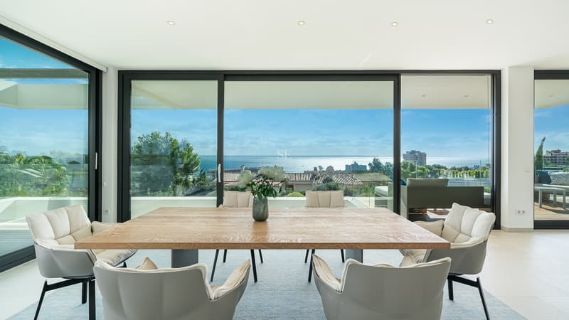 Salle à Manger Moderne avec Vue Panoramique Salle à manger lumineuse avec table en bois et chaises grises face à des baies vitrées avec vue sur l'océan.