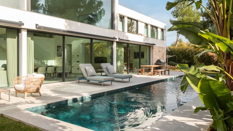 Piscine de luxe dans une villa moderne Piscine turquoise à côté d'une villa blanche moderne avec de grandes baies vitrées et des transats.