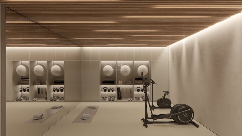 Salle de fitness moderne avec plafond en lattes de bois, appareils cardio, tapis de yoga et poids rangés.