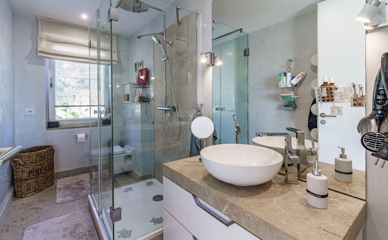 Salle de bain moderne comprenant une cabine de douche en verre, un meuble en pierre naturelle et un grand miroir.