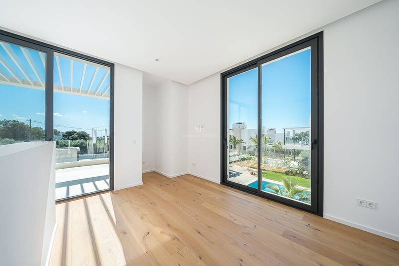 Pièce vide avec parquet en chêne clair, murs blancs et grandes baies vitrées donnant sur une terrasse et une piscine.