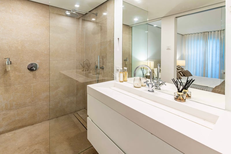 Salle de bains contemporaine avec douche en pierre naturelle, paroi en verre et grand meuble vasque blanc.