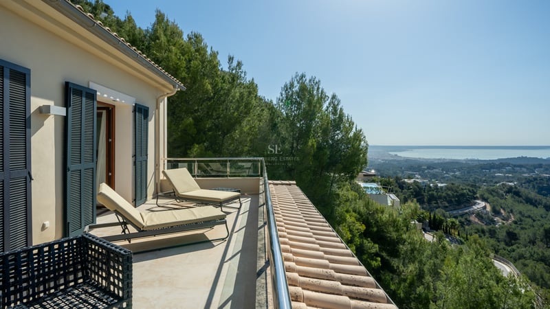 Terrasse de luxe avec bains de soleil, garde-corps en verre et vue imprenable sur la vallée et la mer.