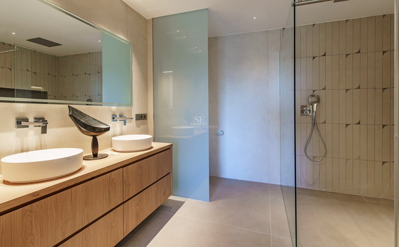 Salle de bains contemporaine avec meuble en bois clair, vasques à poser et grande douche à l'italienne.