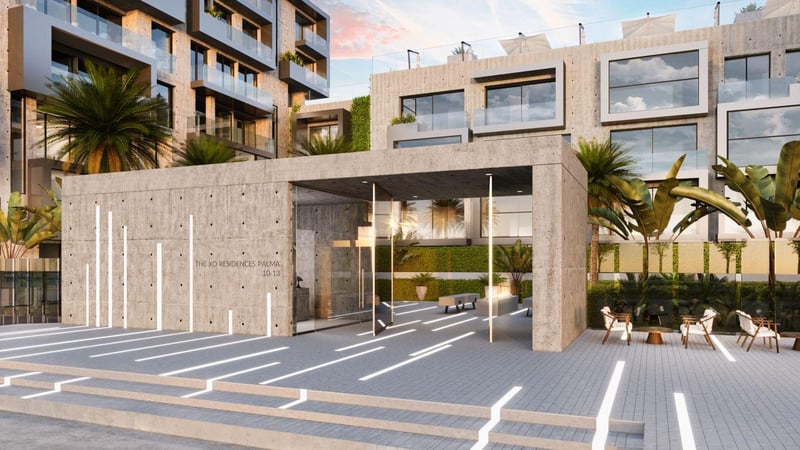 Entrée moderne en béton brut avec éclairage au sol et végétation tropicale.