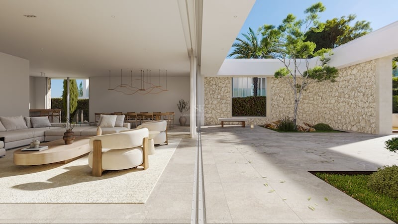 Salon moderne avec portes vitrées coulissantes ouvrant sur une terrasse en pierre, mur en pierre sèche et palmier.