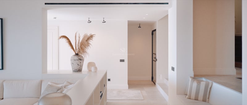 Coin salon encastré avec canapé beige, vase en pierre avec herbe de la pampa et murs blancs épurés.