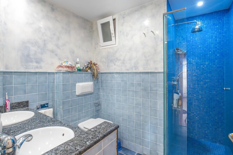 Salle de bain avec carrelage bleu, double vasque en granit et douche en mosaïque bleue.