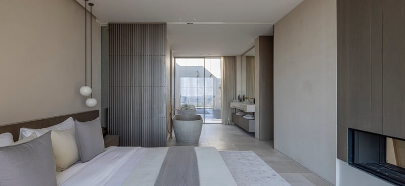 Chambre moderne avec baignoire en pierre îlot, panneaux en bois et baies vitrées toute hauteur.