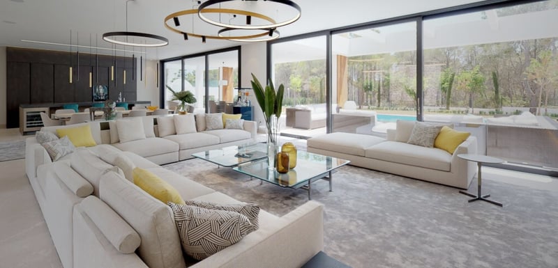 Salon moderne avec canapés crème, tables basses en verre et grandes baies vitrées ouvrant sur une terrasse.