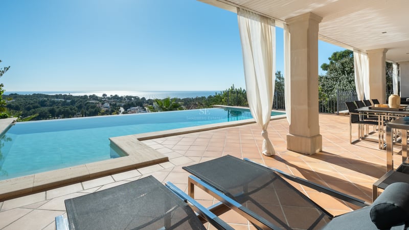 Piscine à débordement sur terrasse en terre cuite avec vue sur la Méditerranée et coin repas ombragé.