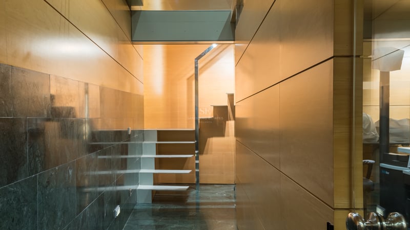 Modern interior hallway featuring light wood paneled walls, polished dark stone floors, and a white floating staircase.
