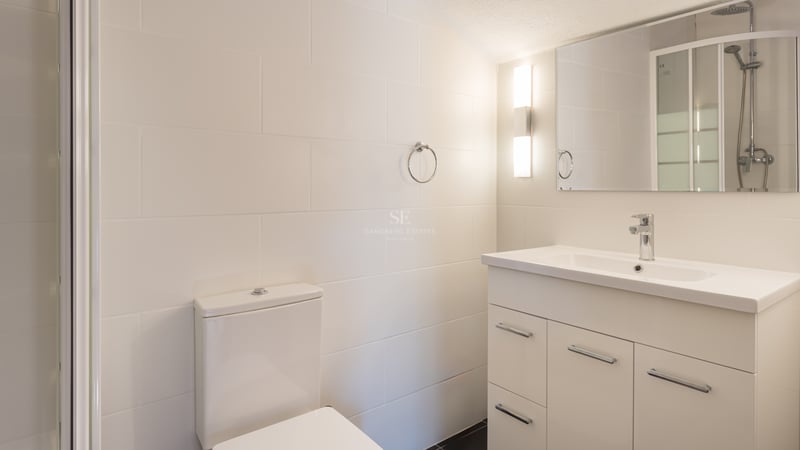 Salle de bain moderne avec carrelage blanc, meuble sous-vasque à tiroirs et robinetterie chromée.