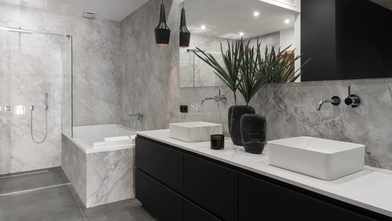 Salle de bain de luxe avec double vasque blanche, meuble noir, baignoire en marbre et douche à l'italienne vitrée.