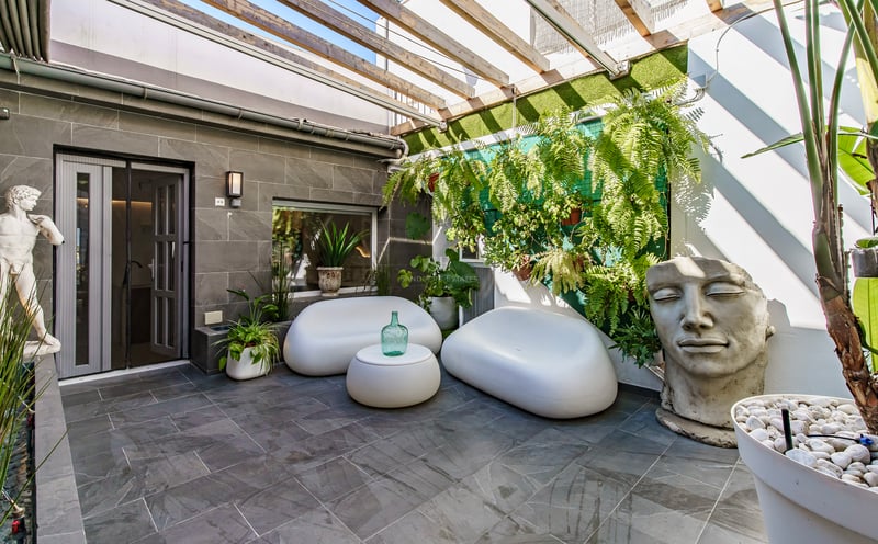 Patio contemporain avec canapés incurvés blancs, dalles en pierre, pergola en bois et une grande sculpture de visage.