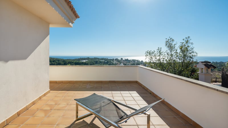 Terrasse ensoleillée avec carrelage en terre cuite et chaise longue moderne surplombant la côte et la mer Méditerranée.