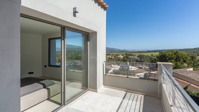 Terrasse privée en pierre naturelle avec baies vitrées coulissantes donnant sur une vallée verdoyante.