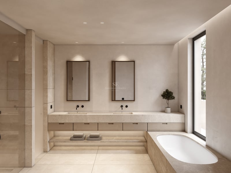 Salle de bain de luxe avec double vasque en pierre, baignoire intégrée et grande fenêtre lumineuse.