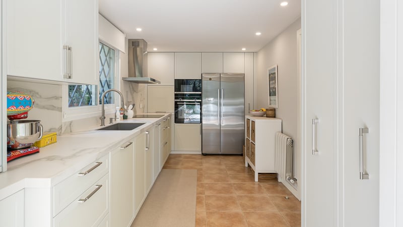 Cuisine contemporaine avec meubles blancs, plans de travail en marbre et appareils en acier inoxydable.