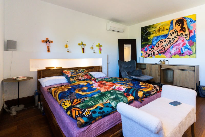 Chambre lumineuse dotée d'un lit avec une literie florale colorée, une grande œuvre d'art moderne et un éclairage encastré.