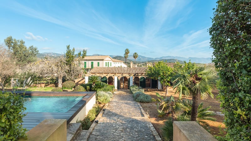Piscine extérieure et chemin de pierre menant à une villa méditerranéenne avec vue sur les montagnes.