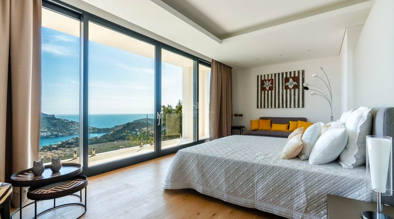 Chambre moderne avec de grandes baies vitrées offrant une vue imprenable sur la mer et la côte.