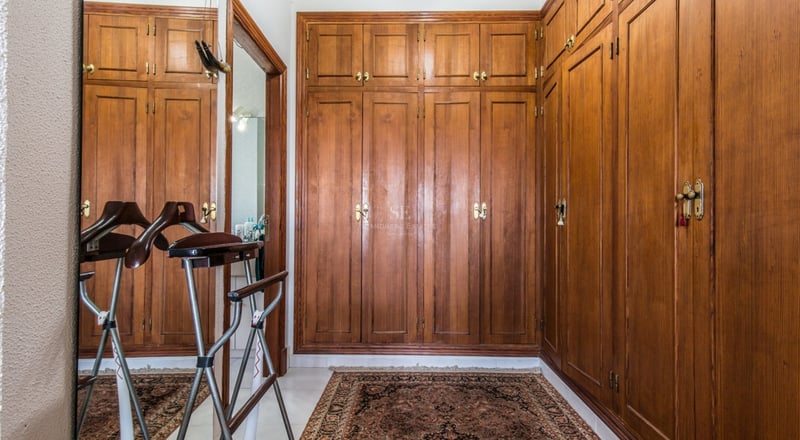 Dressing avec placards intégrés en bois du sol au plafond, tapis persan et valet de nuit.