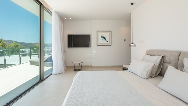 Chambre moderne avec grand lit et baies vitrées coulissantes ouvrant sur une terrasse ensoleillée.