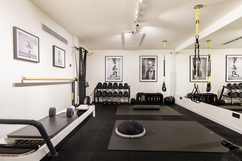Salle de sport moderne avec Reformer Pilates, TRX, poids libres et sol en caoutchouc professionnel.